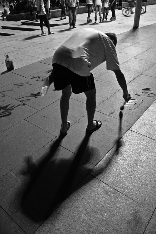 Old Man Practicing Calligraphy on the Sidewalk in Park plaza